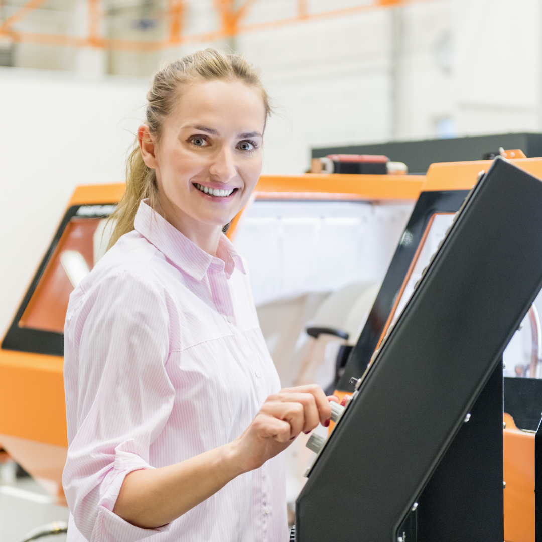 woman smiling at a machine motherboard in a well lit warehouse