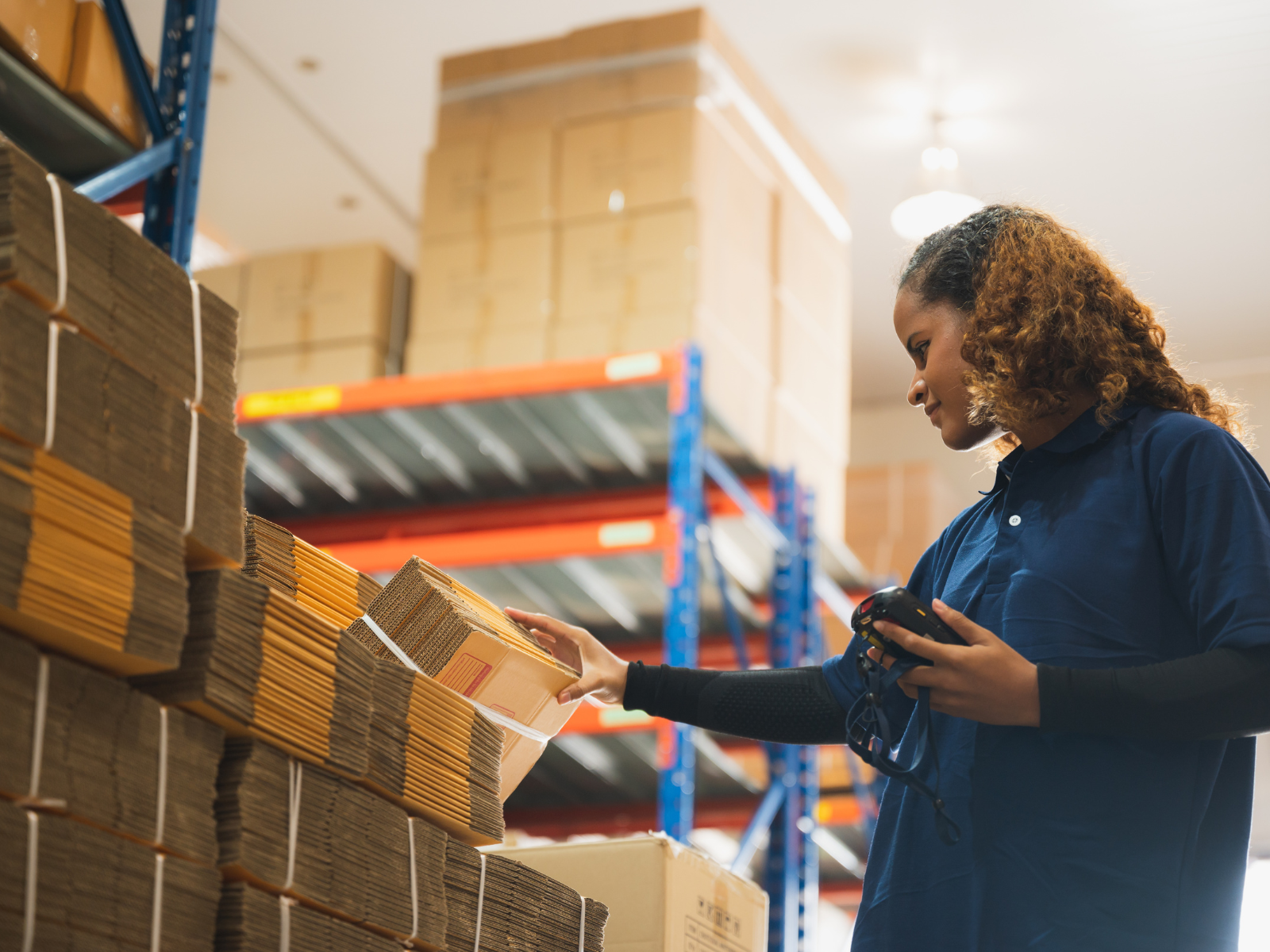 black woman in warehouse scanning boxes and smiling